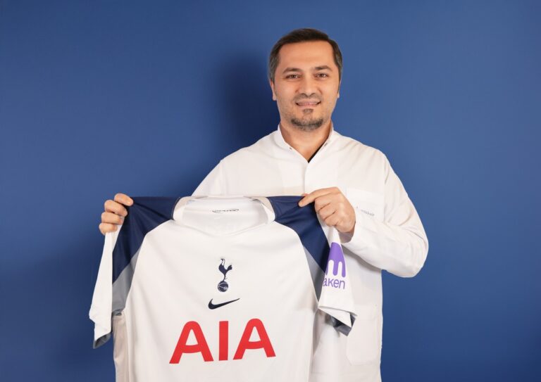 Bild zeigt, wie Dr. Abdulaziz Balwi ein Trikot des Premiere League Klubs Tottenham Hotspur in beiden Hände hält